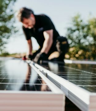 Technician assembling solar panels on house roof for self consumption energy. Renewable energies